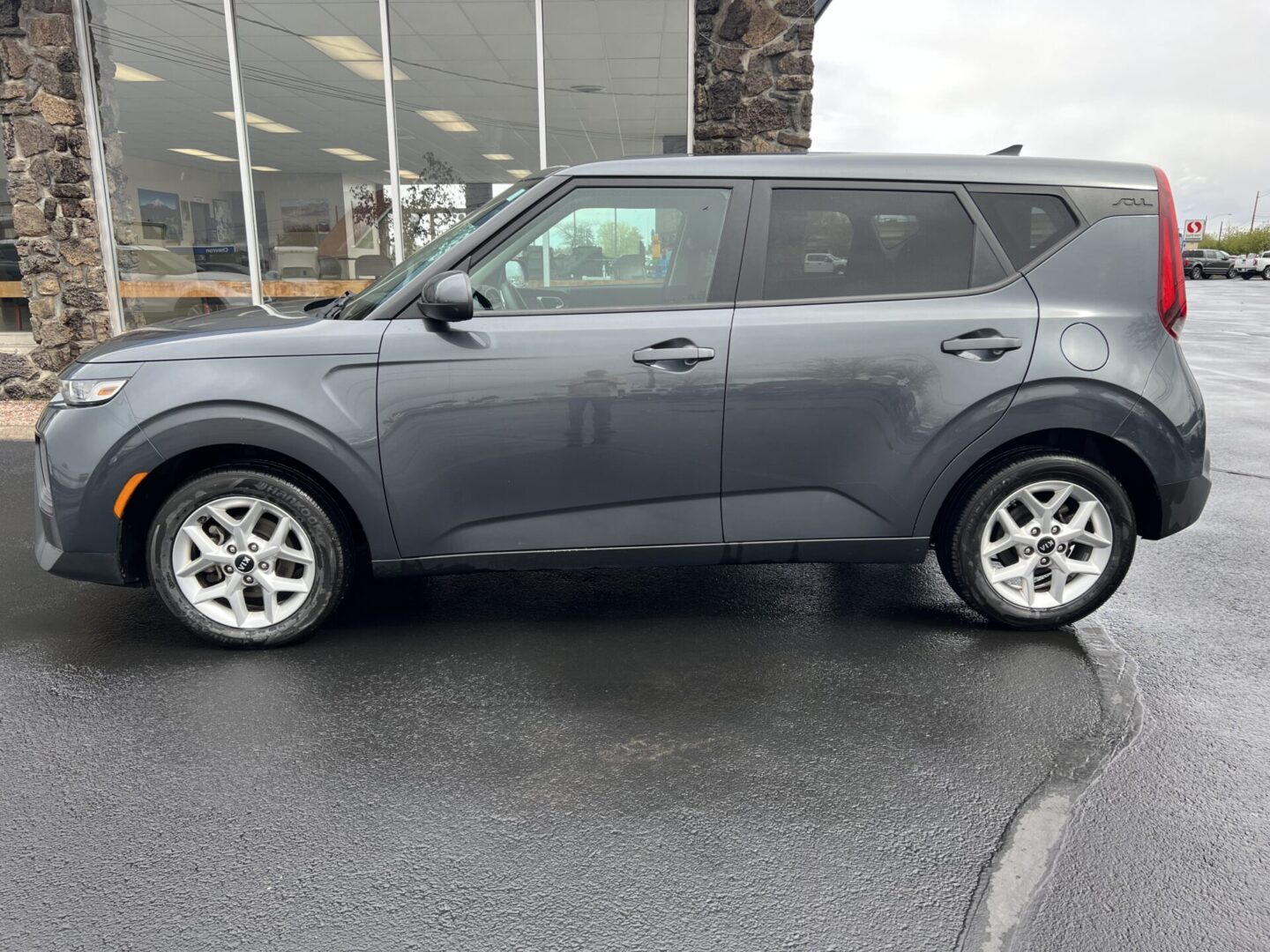 A gray kia soul parked in front of a building.