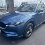 A blue mazda parked on the side of a road.