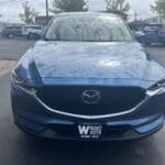 A blue mazda parked in a parking lot.