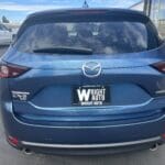 A blue mazda car parked in the lot with another car behind it.