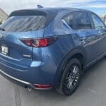 A blue mazda parked on the side of a road.