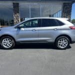 A silver ford edge parked in front of a building.