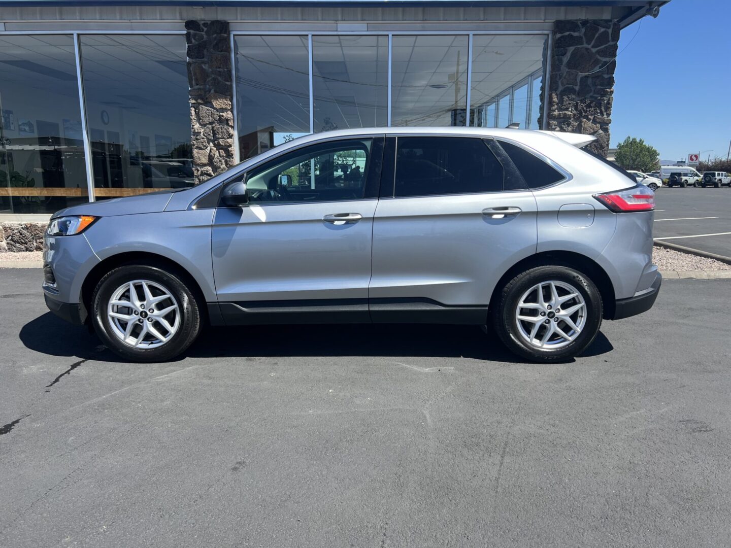 A silver ford edge parked in front of a building.