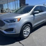 A silver ford edge parked in front of a building.