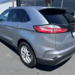 A silver ford edge parked in front of a building.