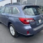 A blue subaru parked in the lot with other cars.