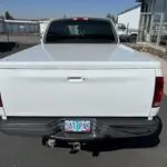 A white truck with its back bumper broken off.